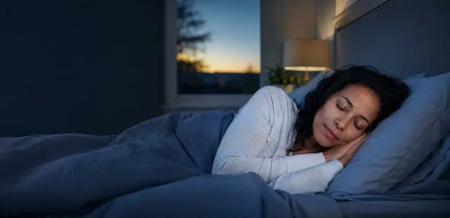 A woman sleeping peacefully in a calm bedroom at dawn