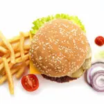 Aerial view of a cheeseburger, toppings, and French fries