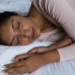 Black woman sleeping soundly in her bed, experiencing REM sleep