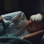 closeup of a woman sleeping in a dark room while wearing an eye mask