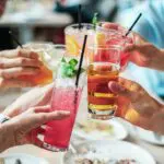 Photograph of group of people doing cheers with various alcoholic drinks, alcohol and sleep